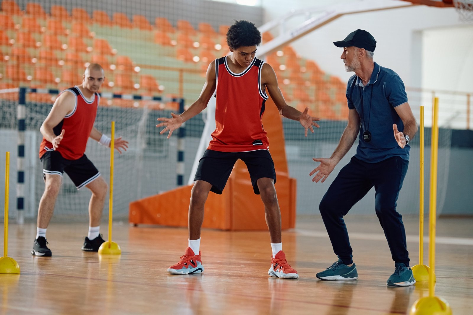 Basketball coach and his players having sports training at school gymnasium.