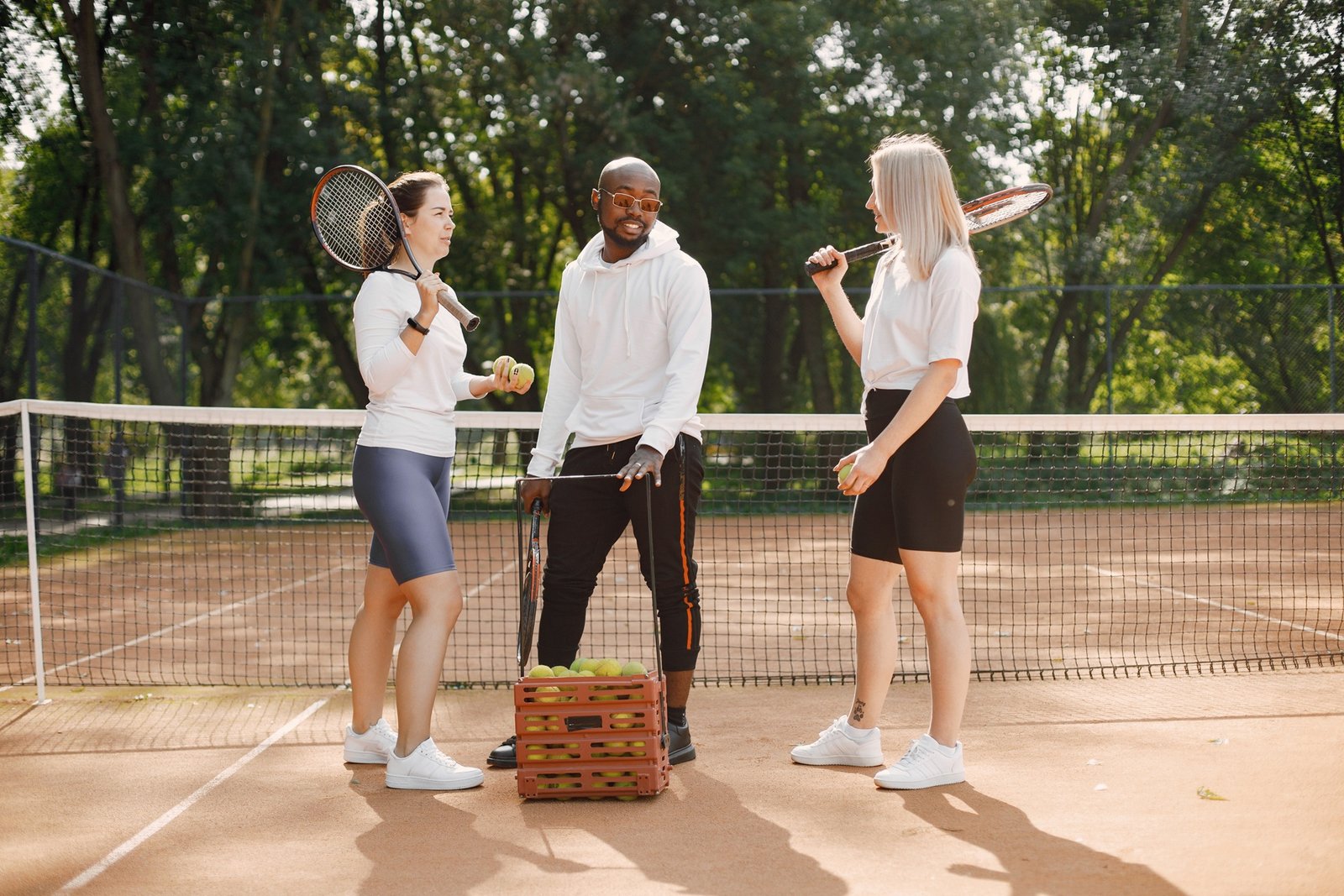 Two women and black race trainer at tennis court